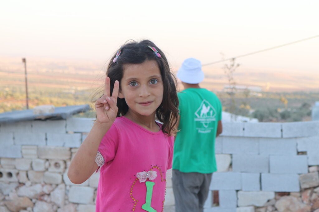 Fillette syrienne dans les camps de réfugiés qui fait le signe de la paix